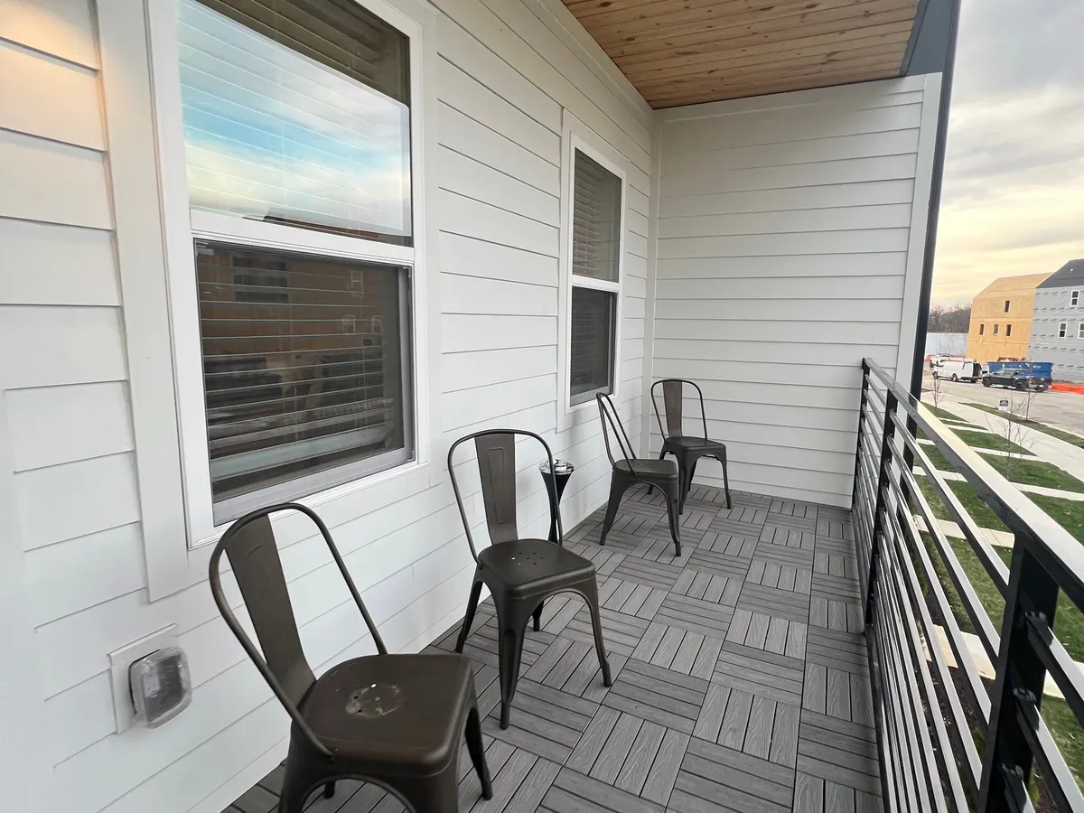 An exterior patio area featuring metal chairs, gray flooring, and railings, ideal for enjoying quiet moments after a busy day or informal team meetings outdoors.