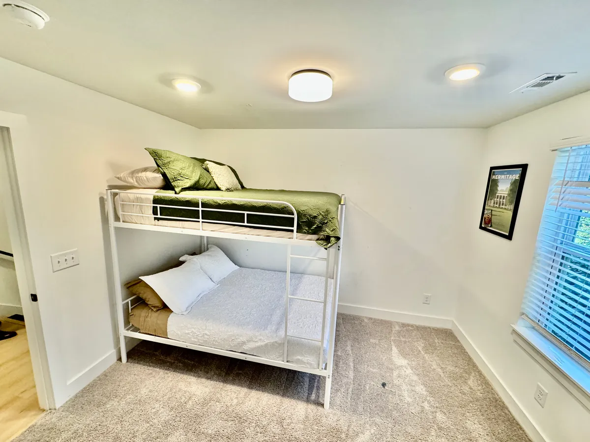 A comfortable bunk bed setup with decorative posters and natural light filtering through the window, creating a fun yet restful environment for families or friends. The space feels inviting and ideal for sleepovers or quiet moments.